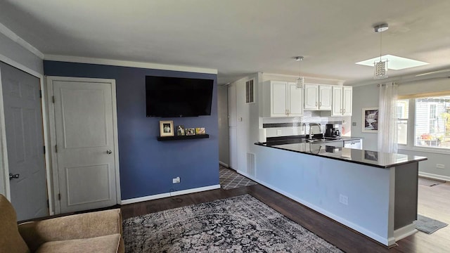 kitchen with white cabinets, wood-type flooring, sink, crown molding, and decorative light fixtures