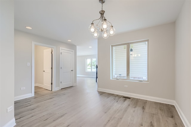 unfurnished room featuring light hardwood / wood-style floors and a chandelier