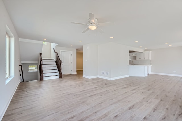 unfurnished living room with sink, light hardwood / wood-style flooring, and ceiling fan