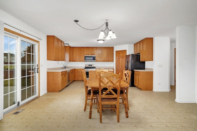 kitchen featuring stainless steel appliances, hanging light fixtures, sink, and an inviting chandelier