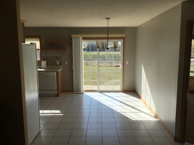 unfurnished dining area featuring light tile patterned floors and a chandelier