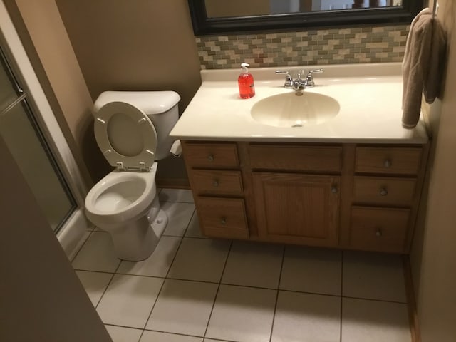 bathroom with vanity, backsplash, tile patterned flooring, toilet, and an enclosed shower