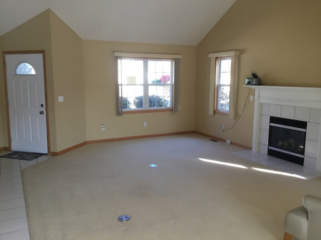 unfurnished living room featuring a tile fireplace, light tile patterned floors, and vaulted ceiling