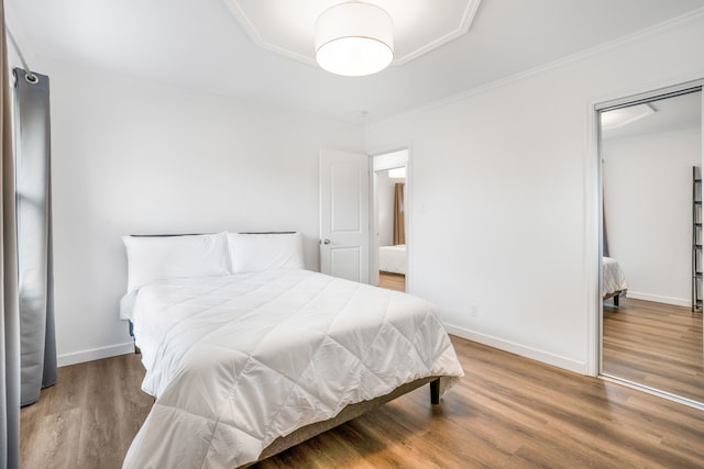 bedroom with a closet, ornamental molding, and wood-type flooring