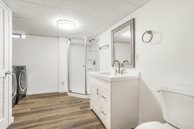 bathroom featuring hardwood / wood-style flooring, toilet, vanity, an enclosed shower, and a drop ceiling