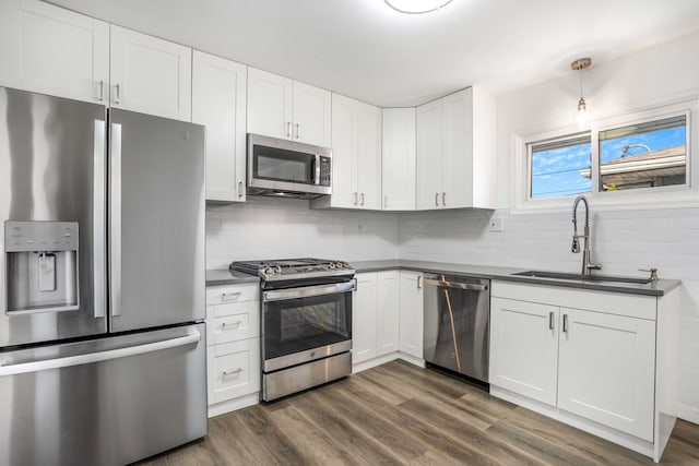 kitchen with sink, white cabinetry, dark hardwood / wood-style flooring, appliances with stainless steel finishes, and tasteful backsplash