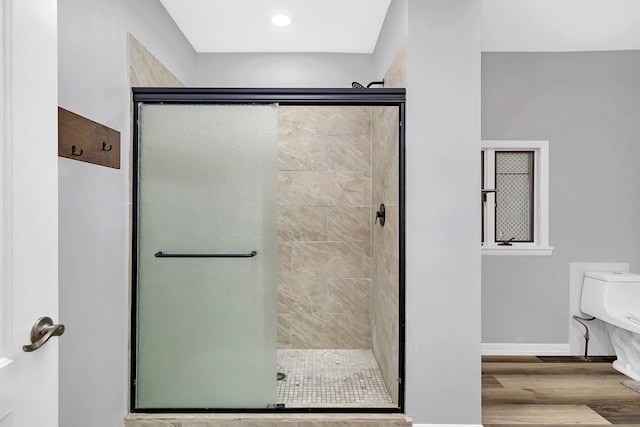 bathroom with a shower with shower door, wood-type flooring, and toilet