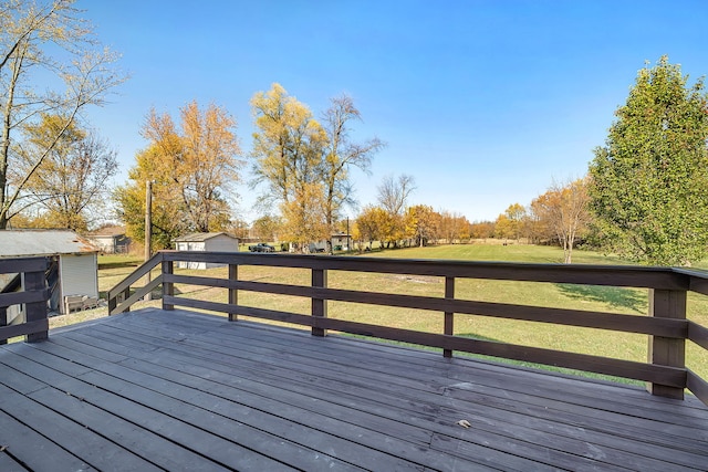 wooden terrace with a storage shed and a lawn