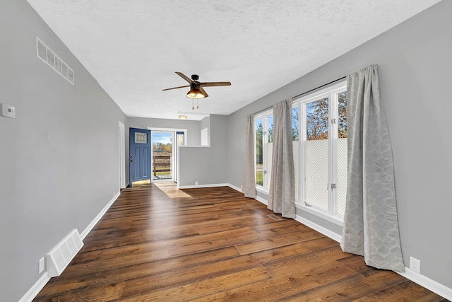 spare room with ceiling fan, a textured ceiling, and dark hardwood / wood-style flooring