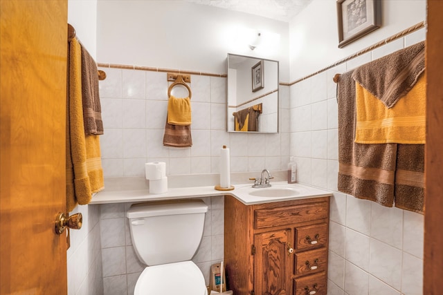 bathroom with tile walls, vanity, and toilet