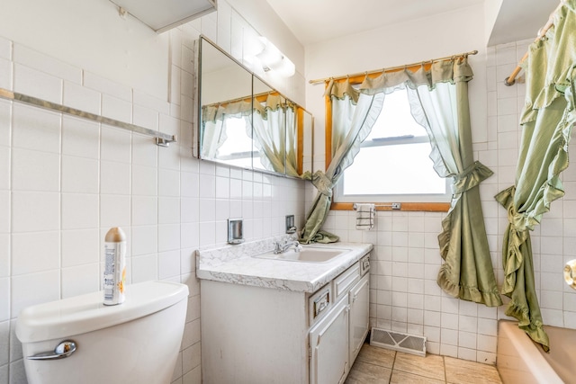 bathroom with toilet, tile patterned floors, tile walls, a bathing tub, and vanity