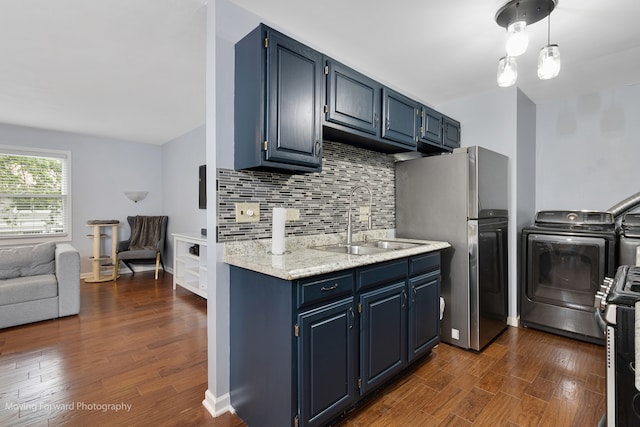 kitchen with dark wood-type flooring, washer / clothes dryer, sink, and stainless steel refrigerator