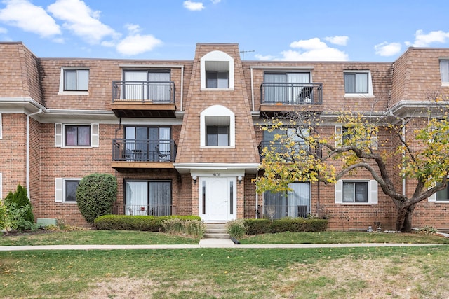 view of front facade featuring a front lawn and a balcony