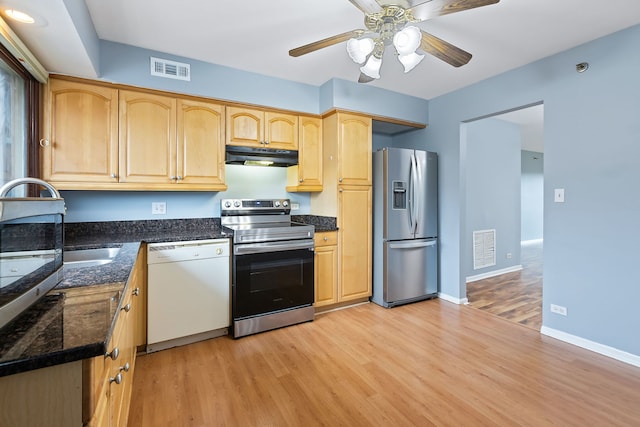 kitchen featuring light hardwood / wood-style floors, dark stone counters, ceiling fan, appliances with stainless steel finishes, and light brown cabinetry