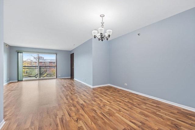 empty room with hardwood / wood-style flooring and a notable chandelier