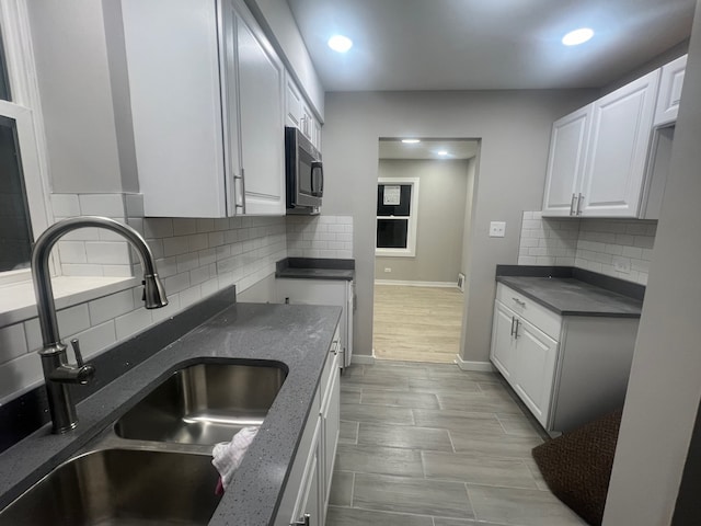 kitchen with light hardwood / wood-style flooring, white cabinets, sink, and backsplash