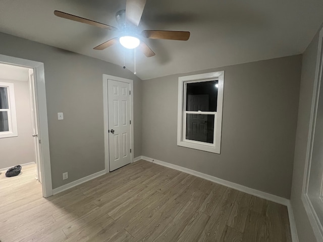 empty room featuring ceiling fan, lofted ceiling, and light hardwood / wood-style flooring