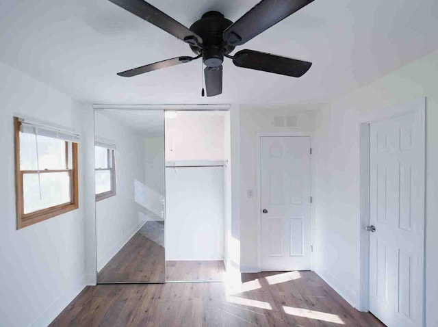 unfurnished bedroom with dark hardwood / wood-style flooring, ceiling fan, and a closet