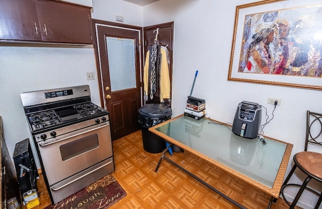 kitchen with stainless steel gas range oven, dark brown cabinetry, and light parquet flooring