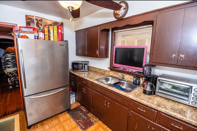 kitchen featuring appliances with stainless steel finishes, dark brown cabinets, light parquet floors, ceiling fan, and sink