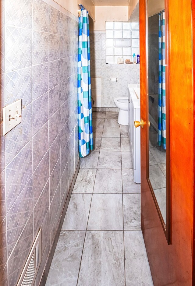 bathroom with vanity, toilet, and tile walls