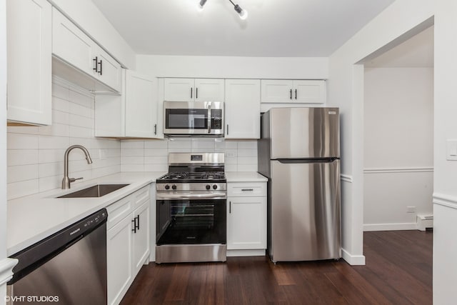 kitchen with sink, appliances with stainless steel finishes, white cabinets, a baseboard heating unit, and dark wood-type flooring