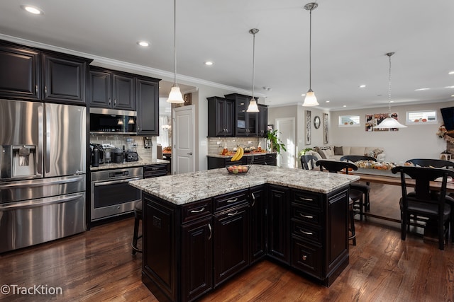 kitchen featuring stainless steel appliances, dark hardwood / wood-style floors, a breakfast bar area, hanging light fixtures, and a kitchen island