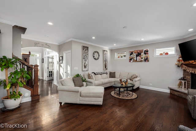 living room with dark wood-type flooring, ornamental molding, and a fireplace