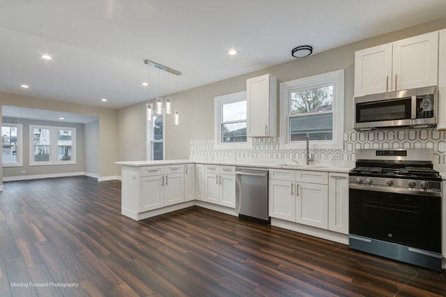 kitchen with stainless steel appliances, kitchen peninsula, tasteful backsplash, dark hardwood / wood-style floors, and white cabinetry