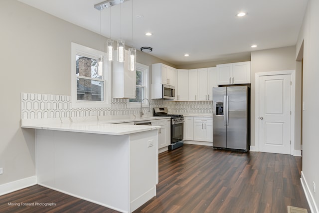 kitchen with stainless steel appliances, decorative light fixtures, dark hardwood / wood-style floors, white cabinets, and kitchen peninsula