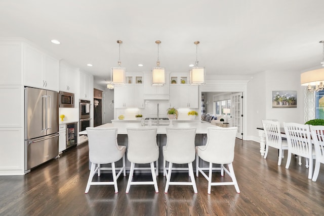 kitchen with white cabinets, plenty of natural light, a large island with sink, and appliances with stainless steel finishes