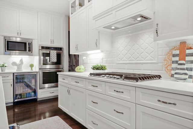 kitchen with backsplash, dark wood-type flooring, white cabinets, appliances with stainless steel finishes, and beverage cooler