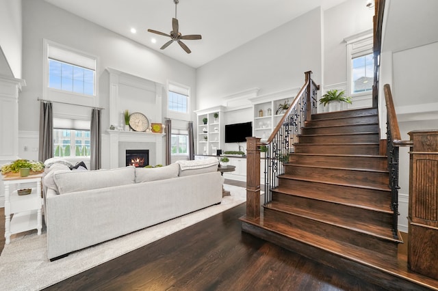 living room with ceiling fan, dark hardwood / wood-style flooring, a healthy amount of sunlight, and a high ceiling