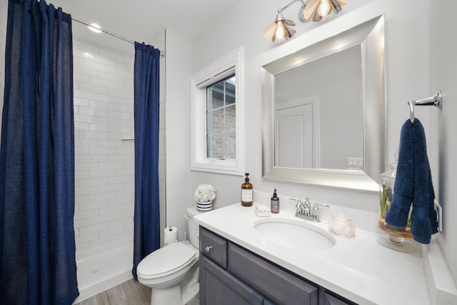 bathroom with hardwood / wood-style floors, vanity, toilet, and walk in shower