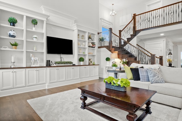 living room with a towering ceiling, dark hardwood / wood-style floors, and a notable chandelier