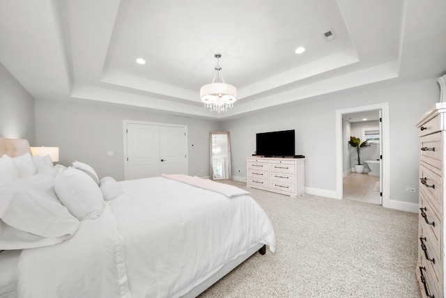 carpeted bedroom featuring a raised ceiling, connected bathroom, and a closet