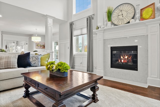 living room featuring a high ceiling, dark hardwood / wood-style flooring, and ornate columns