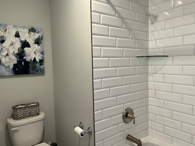 bathroom featuring tiled shower / bath combo and toilet