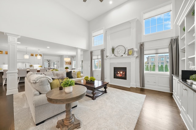 living room featuring wood-type flooring, a towering ceiling, and ceiling fan