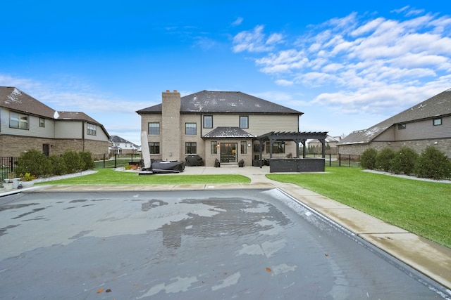 rear view of house with a lawn, a pergola, a patio, and a covered pool