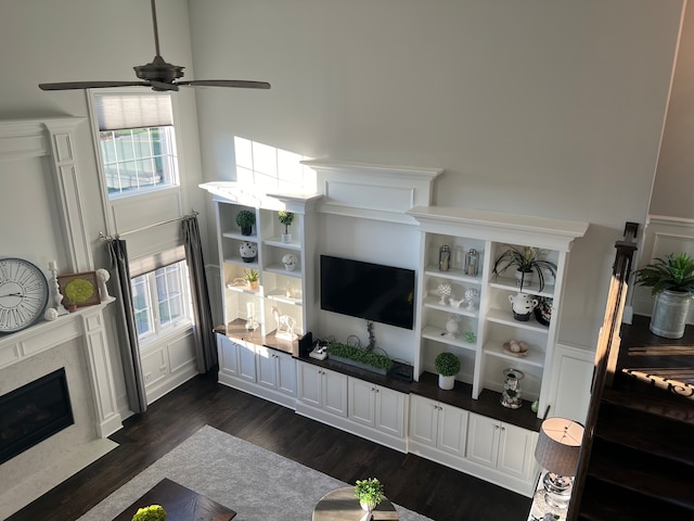 living room with ceiling fan, a high end fireplace, and dark hardwood / wood-style floors