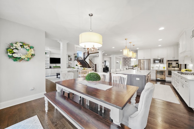 dining space featuring decorative columns, wine cooler, dark wood-type flooring, and a notable chandelier