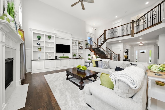 living room featuring a towering ceiling, dark hardwood / wood-style flooring, and ceiling fan