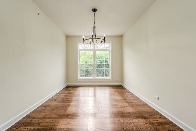 empty room featuring dark hardwood / wood-style floors and a chandelier