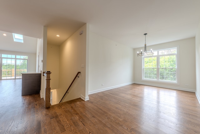 spare room with a chandelier, a skylight, and dark hardwood / wood-style flooring