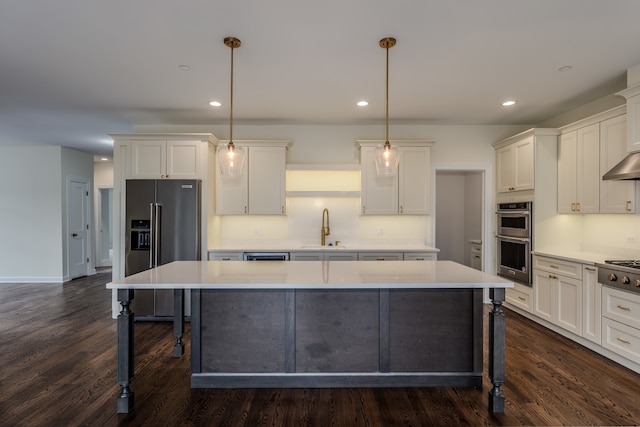 kitchen featuring stainless steel appliances, dark wood-type flooring, hanging light fixtures, sink, and a kitchen island