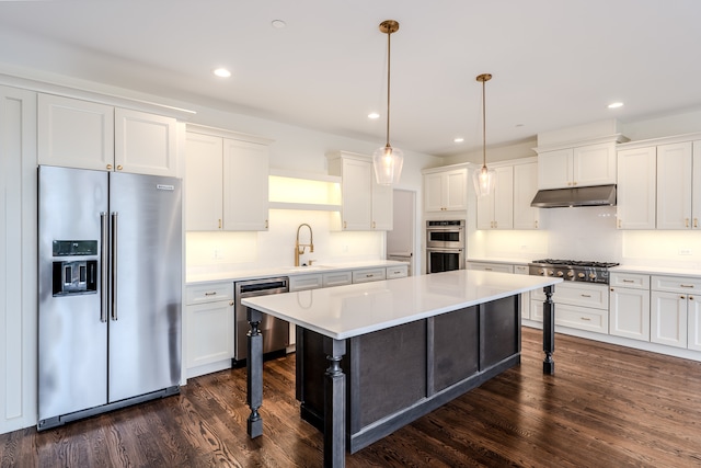 kitchen with dark wood-type flooring, white cabinets, a kitchen island, pendant lighting, and appliances with stainless steel finishes