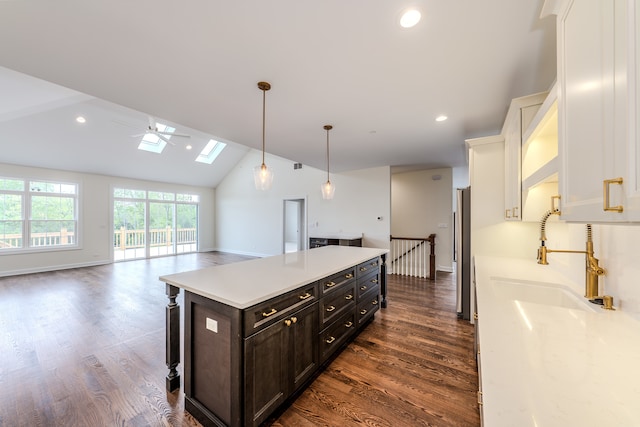 kitchen featuring a kitchen island, decorative light fixtures, dark hardwood / wood-style flooring, white cabinets, and lofted ceiling with skylight