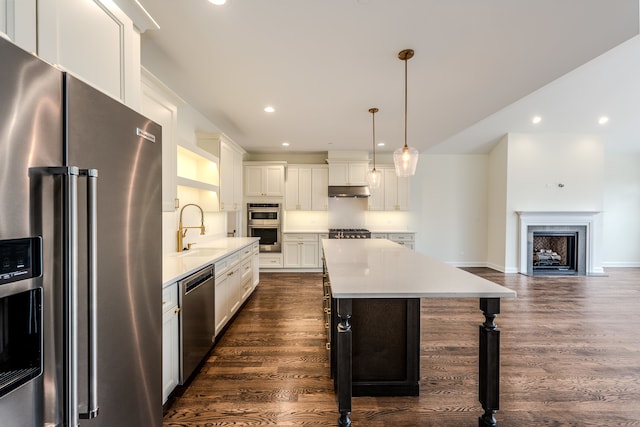 kitchen with stainless steel appliances, pendant lighting, sink, white cabinets, and dark wood-type flooring