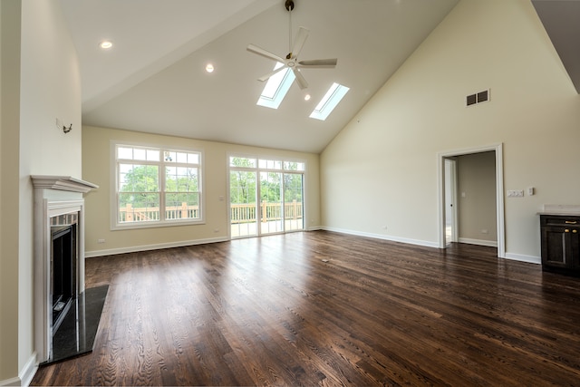 unfurnished living room with high vaulted ceiling, dark wood-type flooring, ceiling fan, and a skylight